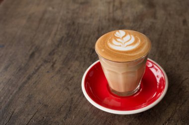 Küçük bardakta Piccolo Latte sanatı. Kırmızı seramik tabakla sütten güzel çiçek sanatı..