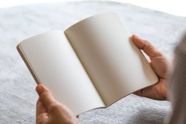 Masanın üzerinde boş bir kitap okuyan kadın, boş boşluğa imgenizi ya da mesajınızı girin.