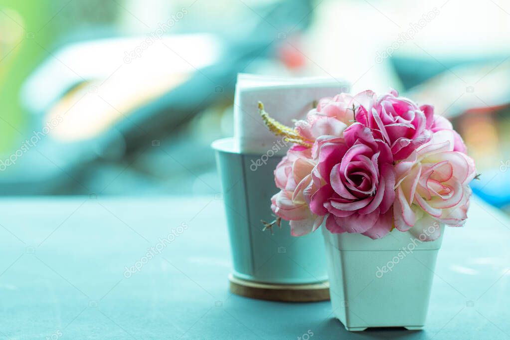 artificial pink roses flower on wooden desk with copy space for love background or vintage valentine background, filterred to pastel color tone.