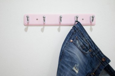 Beyaz duvarda asılı mavi kot pantolon.
