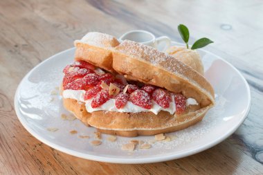 Vanilyalı dondurmayı waffle ve ahşap masa arkasında taze çilekle kapat..