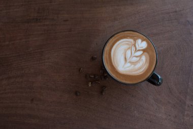 Tahta masadaki bir fincan sıcak latte sanat kahvesi..