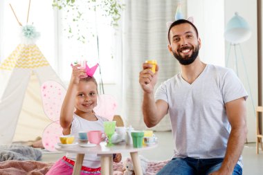 Baba ile kızı birlikte evde oynarken, halı üzerinde oturan ve sevimli oyuncak parti düzenleme. 