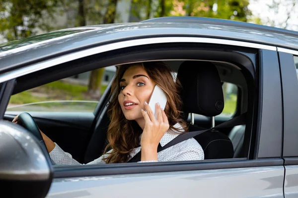 車の運転と同時に スマート フォンを話している若い女性 — ストック写真