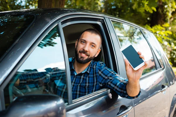 笑みを浮かべてクラウドソーシングのタクシーの運転手は車に座って 携帯電話を手で保持しています — ストック写真