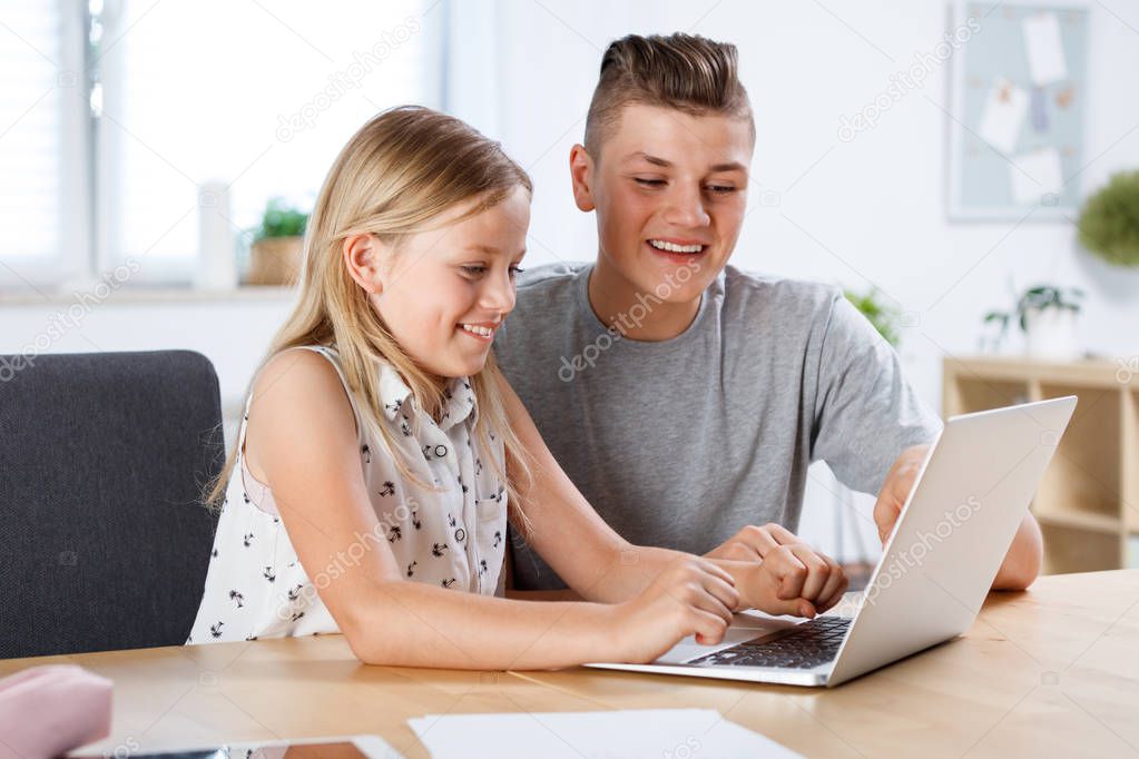 Teenagers sitting at the table at home and using digital tablet together. 