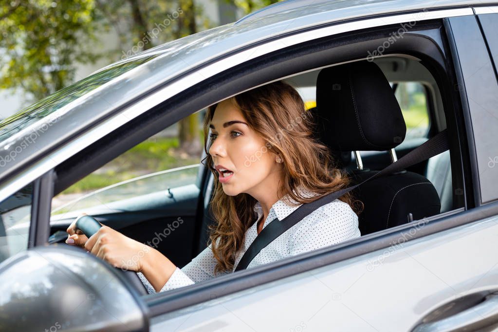Side view of upset young woman driving a car. 