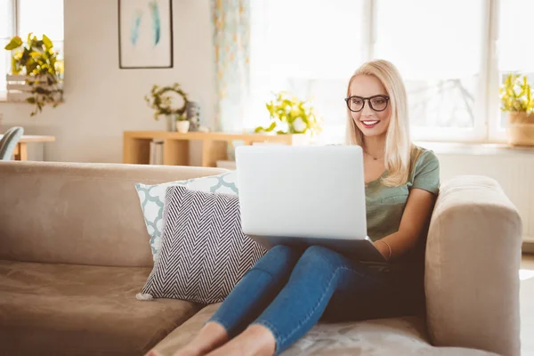 Uśmiechnięta Młoda Blondynka Kobieta Siedzi Kanapie Domu Korzysta Laptopa — Zdjęcie stockowe