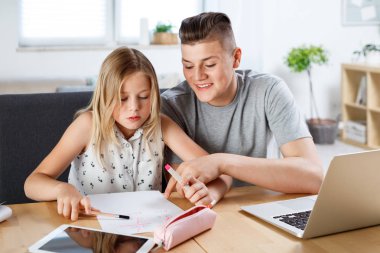 Erkek ve kız masada evde oturuyor. Kardeşim onun siter eve yardımcı oluyorlar.