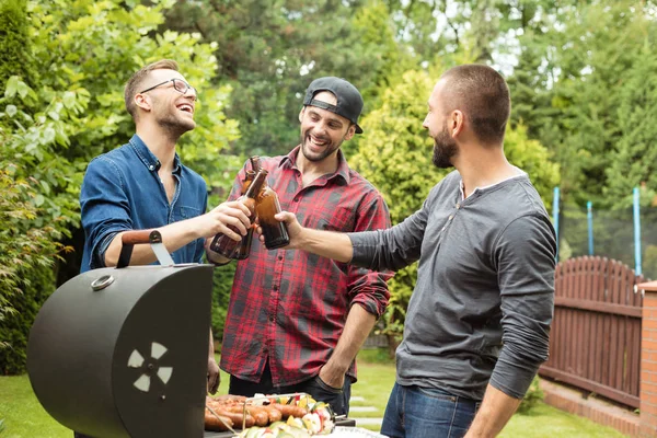 Üç arkadaş bira şişeleri ile toasting Barbekü eğleniyor açık atış. 