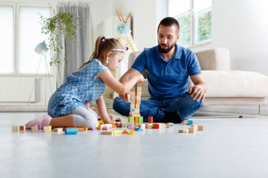 Babası blokları ile birlikte evde oynarken, oturma odasında katta oturan kızı ile. 
