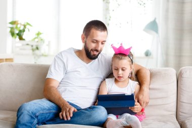 Baba ve kızı evde kanepede oturan ve dijital tablet birlikte kullanma. 