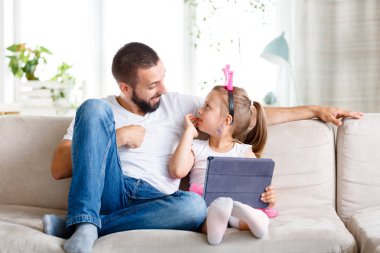 Baba ve kızı evde kanepede oturan ve dijital tablet birlikte kullanma. 