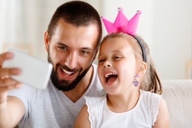 Selfie sevimli küçük kızını alarak mutlu genç baba. Yüzler yakın çekim. 