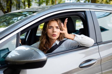 Sinir bozucu genç kadın bir araba yan görünüm. 