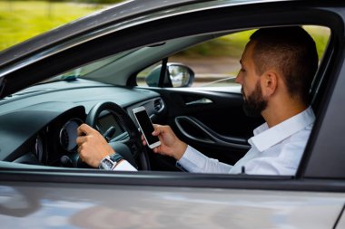 Genç işadamı cep telefonu aynı zamanda sürüş araba ve manifatura yan görünüm. 