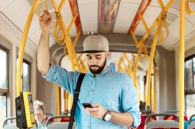 Genç adam manifatura otobüsteki akıllı telefon üzerinde sakallı.