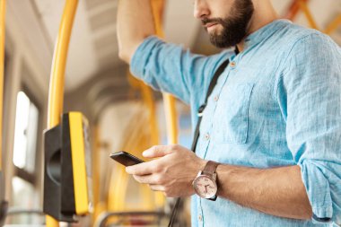 Genç adam manifatura otobüsteki akıllı telefon üzerinde sakallı.
