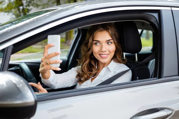 車の運転と同時に Selfie を取って笑顔の若い女性 — ストック写真