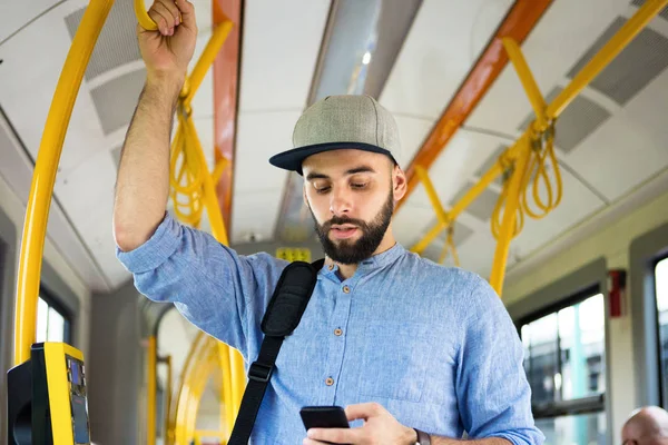 Genç adam manifatura otobüsteki akıllı telefon üzerinde sakallı.