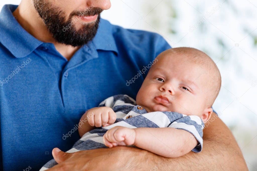 Happy young father holding his baby boy at home. Close up of face. 