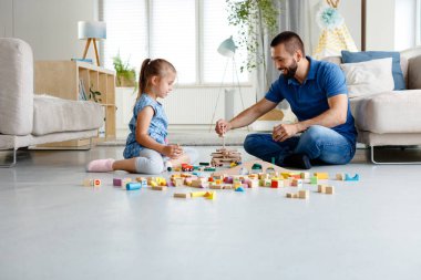 Babası blokları ile birlikte evde oynarken, oturma odasında katta oturan kızı ile. 