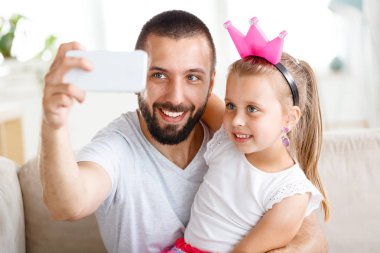 Selfie sevimli küçük kızını alarak mutlu genç baba. Yüzler yakın çekim. 