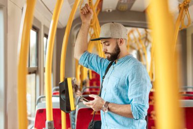 Genç adam manifatura otobüsteki akıllı telefon üzerinde sakallı.