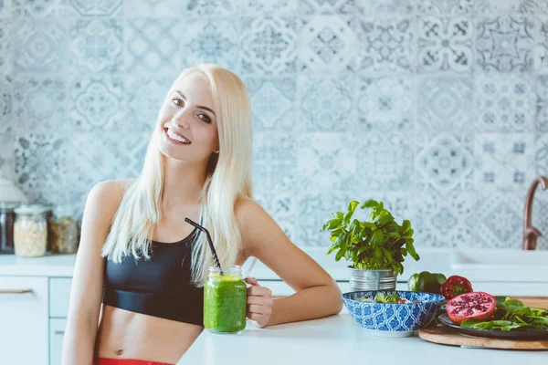 Mulher Bonita Vestindo Roupas Esportivas Sentado Cozinha Segurando Smoothie Verde — Fotografia de Stock