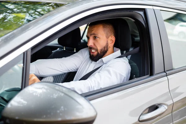 車を運転して欲求不満の若いひげを生やした男の側面図 — ストック写真