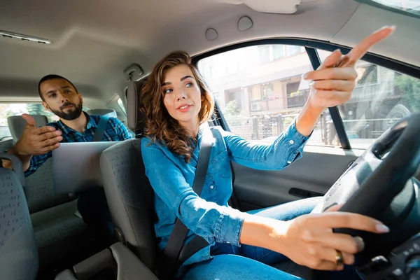 男性乗客と話して女性タクシー ドライバー ノート パソコンを使用している人 — ストック写真