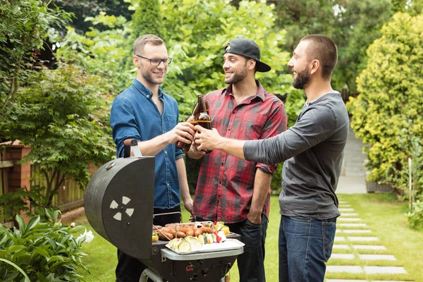 Üç arkadaş bira şişeleri ile toasting Barbekü eğleniyor açık atış. 