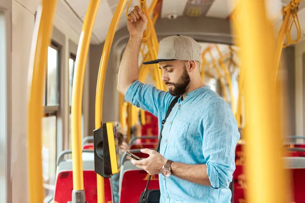 年轻的胡须男子在公交车上用智能手机发短信 — 图库照片