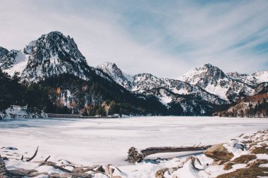 Katalonya 'daki Aiguestortes Ulusal Parkı' nda karla kaplı gölü ve dağları olan bir vadinin kış manzarası.