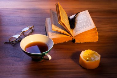 Masanın üzerinde açık bir kitap. Kasvetli yanan muma. yakın çekim