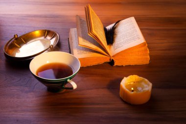 Masanın üzerinde açık bir kitap. Kasvetli yanan muma. yakın çekim