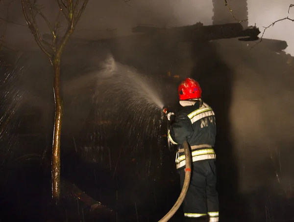 Firefighters extinguish the house. Night, it\'s snowing.