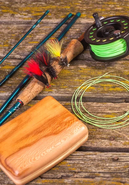 fly fishing rod with a coil and flies lie on old, wooden boards