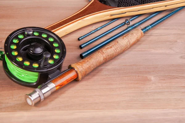 fly fishing rod with a coil and flies lie on old, wooden boards