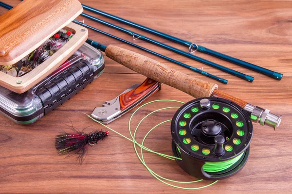 fly fishing rod with a coil and flies lie on old, wooden boards