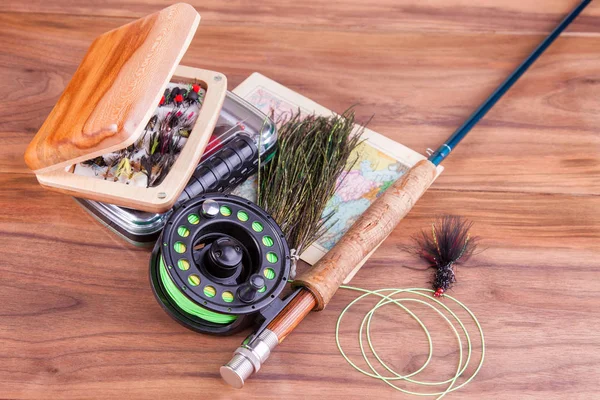 fly fishing rod with a coil and flies lie on old, wooden boards