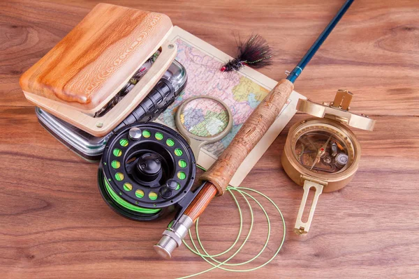 fly fishing rod with a coil and flies lie on old, wooden boards