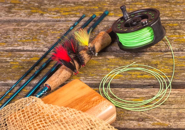 fly fishing rod with a coil and flies lie on old, wooden boards