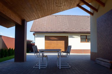 Bahçe masa, sandalye gölgede bir gölgelik altında hazır. Sıcak güneşli gün garaja yakın.