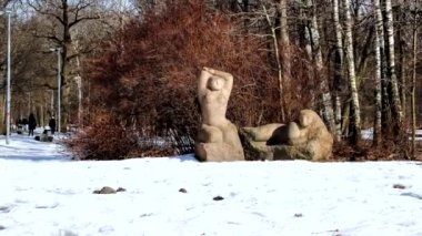 parkta, arka planda geçen insanlar heykel
