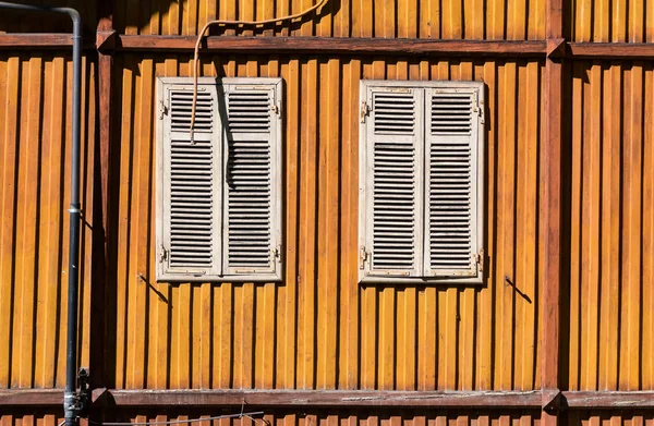 Italy. Building\'s wall in sunny day. Orange wall with two windows.