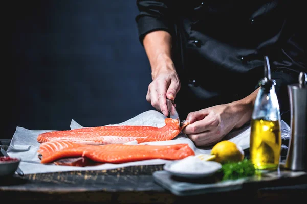 big salmon in hands of chef cook. man using knife to slice salmon fillet