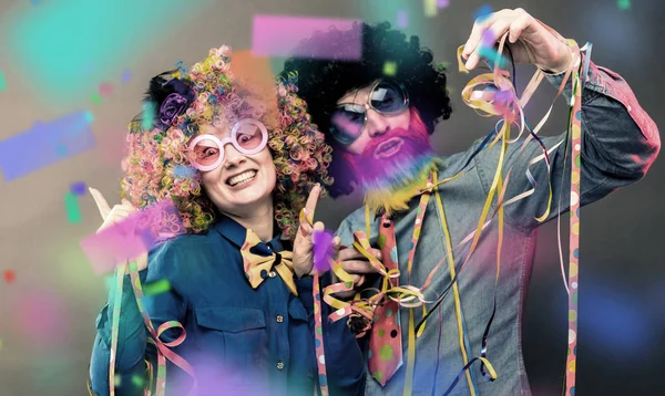 Happy man and woman wearing color wigs with party items