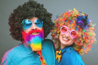 Happy man and woman wearing color wigs with party items clipart