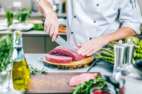 料理レストラン キッチン シェフ 彼は肉やステーキを切っています — ストック写真